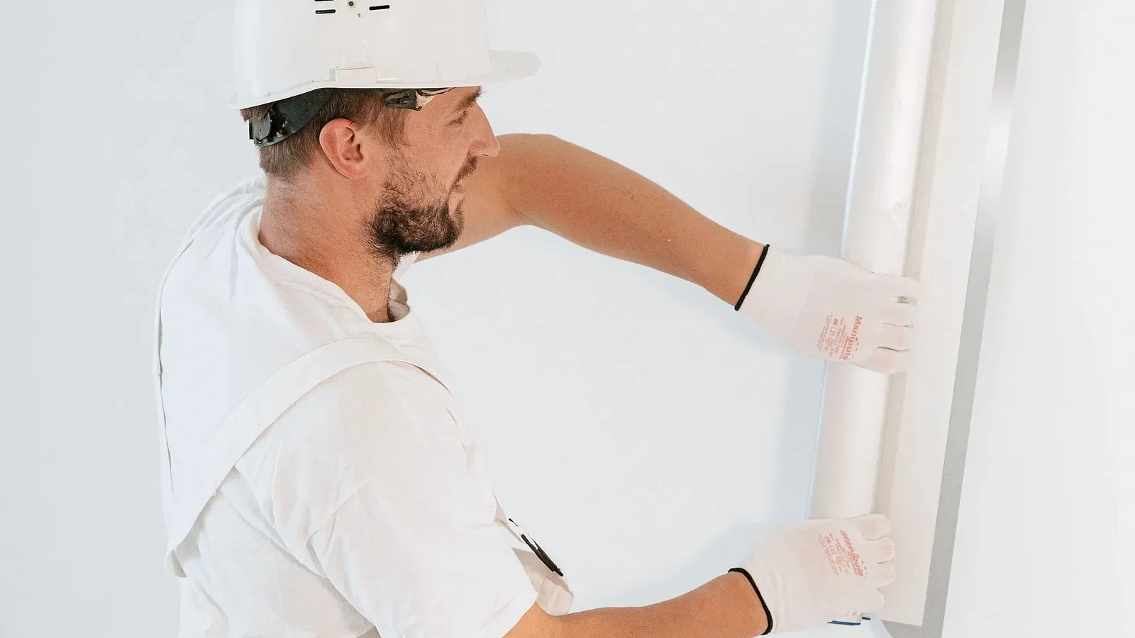 Handwerker montiert eine Gipsplatte an einer Trockenbauwand